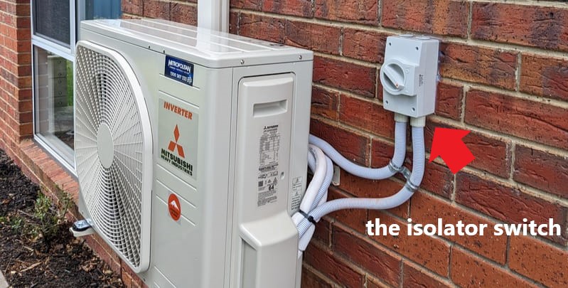 isolator switch on brick wall next to outdoor unit of a Mitsubishi inverter air conditioner.