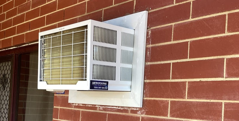 window air conditioner installed on red brick wall of a home