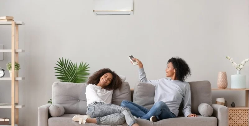 What are the Cheapest Air Conditioners to Run? happy family relaxing on sofa under air conditioner