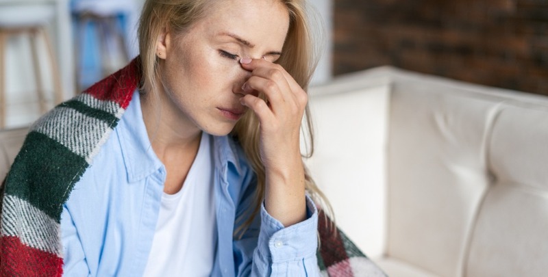 tired woman with closed eyes touching nose bridge