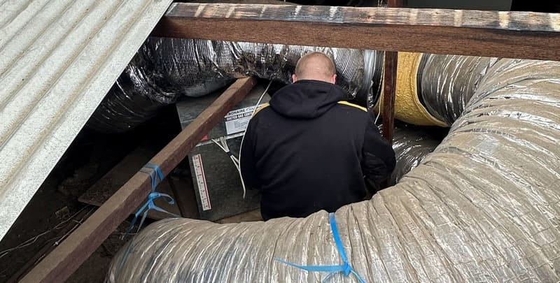 A Metro AC technician servicing air ducts